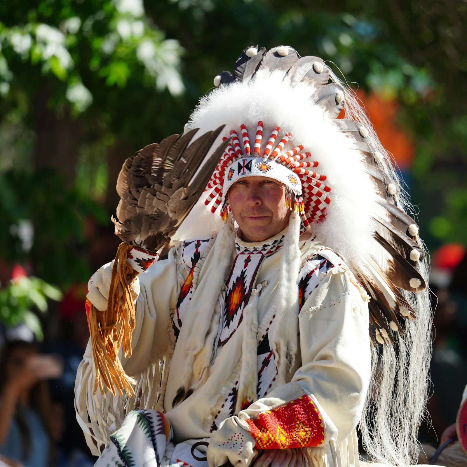 A Native American man in traditional clothing and feathered headdress during a cultural ceremony.