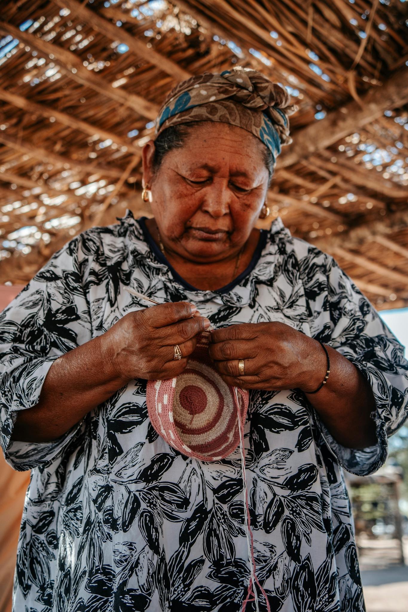 Elderly indigenous woman skillfully weaving a basket in Guajira, Colombia.